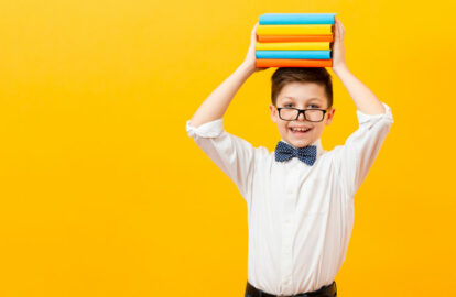 young boy holding a stack of books on his head