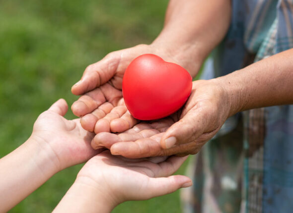 adult handing a red plastic heart to a child